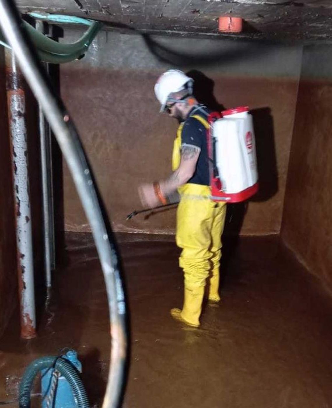 Técnico aplicando tratamiento dentro de un tanque de reserva impermeabilizado