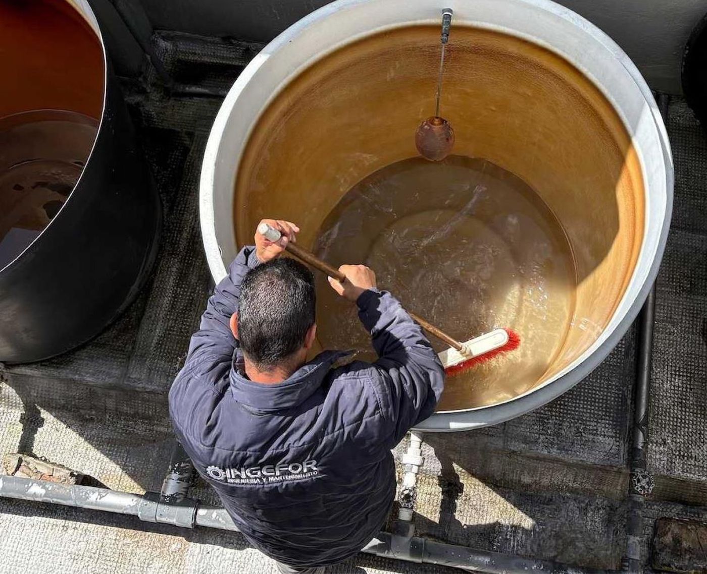 Técnico de INGEFOR lavando un tanque de reserva elevado